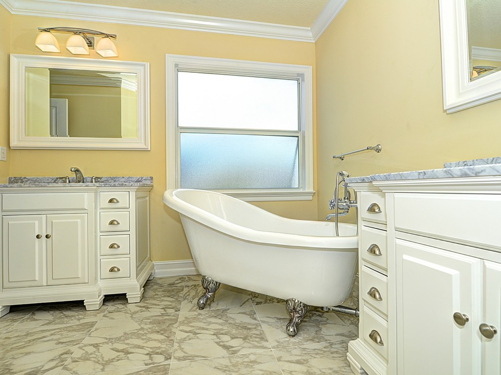 Inspiration for a large traditional master bathroom in Miami with an undermount sink, raised-panel cabinets, white cabinets, a claw-foot tub, a two-piece toilet, yellow walls, marble floors, marble benchtops and multi-coloured floor.