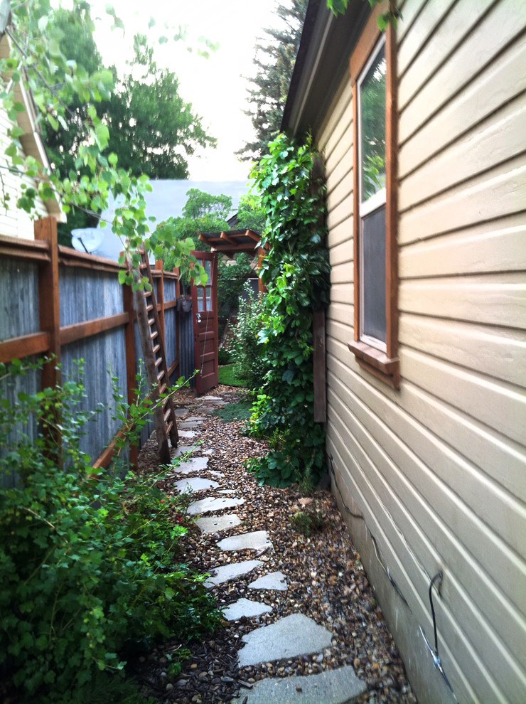 Small eclectic side yard full sun garden in Salt Lake City with a garden path and natural stone pavers.