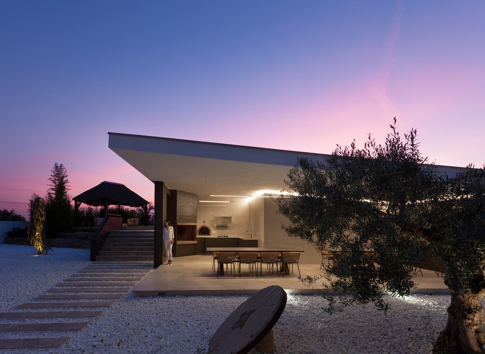 Diseño de terraza minimalista en anexo de casas con cocina exterior y suelo de baldosas