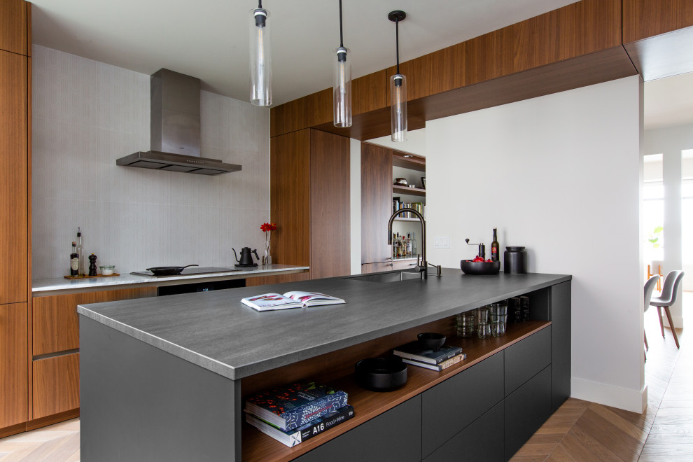Photo of a modern eat-in kitchen in Seattle with an undermount sink, flat-panel cabinets, dark wood cabinets, solid surface benchtops, white splashback, ceramic splashback, panelled appliances, medium hardwood floors, with island, brown floor and grey benchtop.