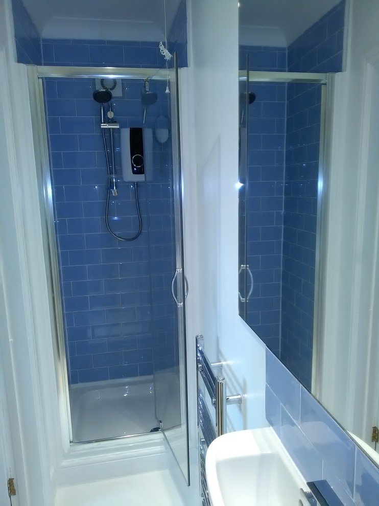 Design ideas for a small contemporary 3/4 bathroom in Hertfordshire with flat-panel cabinets, white cabinets, an alcove shower, a two-piece toilet, blue tile, ceramic tile, white walls, linoleum floors and a console sink.