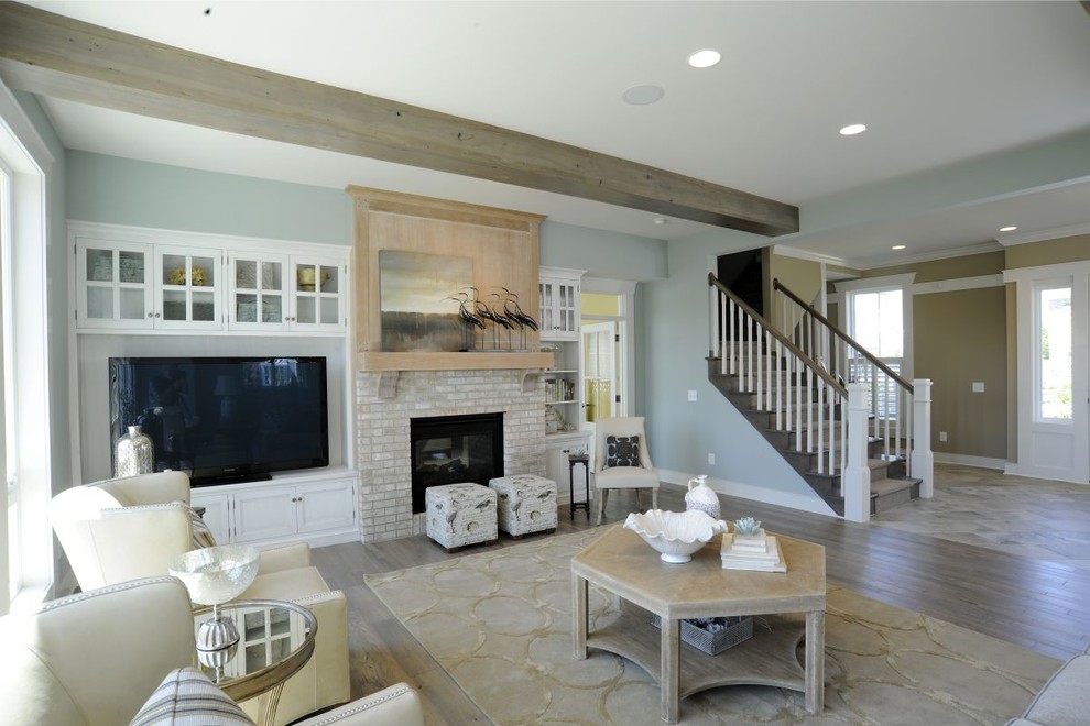 This is an example of a beach style formal open concept living room in Columbus with blue walls, vinyl floors, a standard fireplace, a brick fireplace surround, a built-in media wall, grey floor and exposed beam.