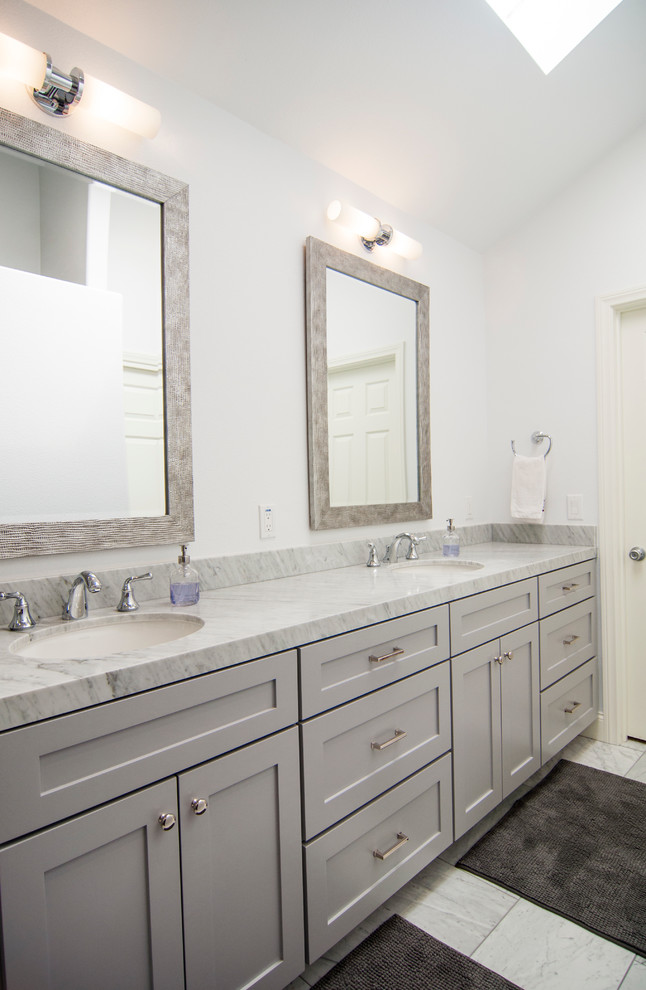 Design ideas for a mid-sized transitional master bathroom in Los Angeles with recessed-panel cabinets, grey cabinets, an alcove shower, gray tile, white tile, stone tile, grey walls, marble floors, an undermount sink and marble benchtops.