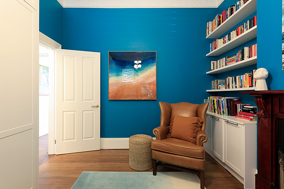 Inspiration för ett litet vintage gästrum, med blå väggar, mellanmörkt trägolv, en standard öppen spis, en spiselkrans i trä och brunt golv