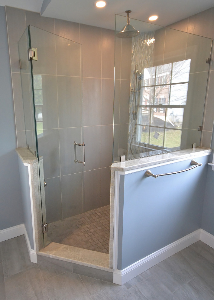 Design ideas for a mid-sized transitional master bathroom in Philadelphia with recessed-panel cabinets, white cabinets, a freestanding tub, a corner shower, a one-piece toilet, beige tile, porcelain tile, blue walls, ceramic floors, an undermount sink, quartzite benchtops, grey floor, a hinged shower door and beige benchtops.