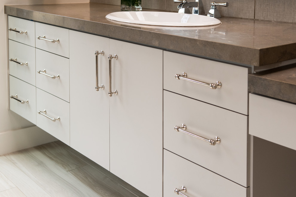 Mid-sized transitional master gray tile and cement tile light wood floor and beige floor drop-in bathtub photo in Dallas with flat-panel cabinets, gray cabinets, gray walls, a drop-in sink, concrete countertops and a hinged shower door