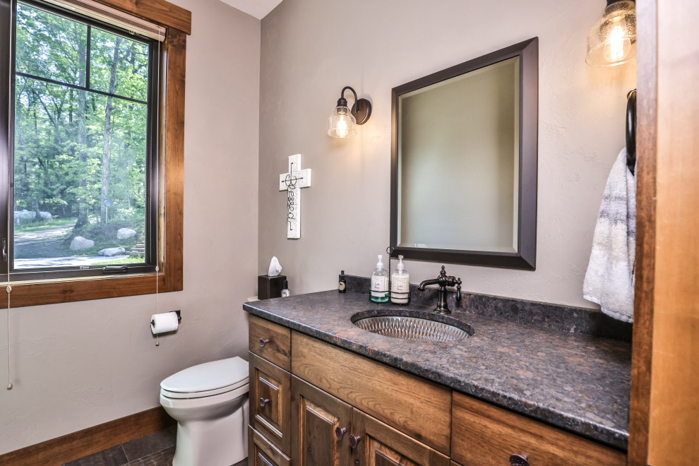 Klassisk inredning av ett flerfärgad flerfärgat toalett, med luckor med upphöjd panel, skåp i mellenmörkt trä, en toalettstol med separat cisternkåpa, grå väggar, klinkergolv i porslin, ett undermonterad handfat och flerfärgat golv