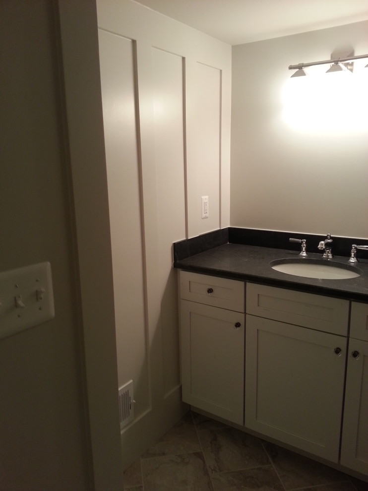 Small arts and crafts bathroom in Detroit with linoleum floors, shaker cabinets, white cabinets, a two-piece toilet, gray tile, grey walls, an undermount sink and solid surface benchtops.