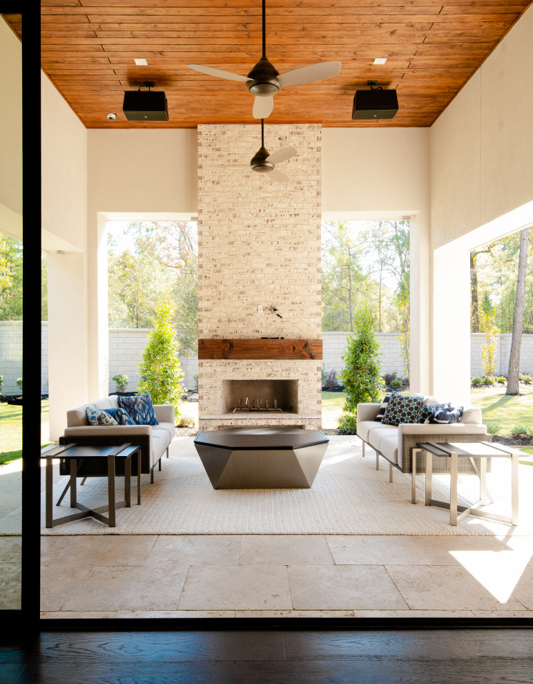 Foto di un patio o portico design dietro casa con un caminetto, piastrelle e un tetto a sbalzo