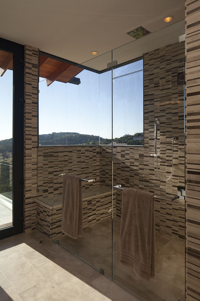 Inspiration for a large contemporary master bathroom in Austin with a curbless shower, beige tile, flat-panel cabinets, medium wood cabinets, a drop-in tub, stone tile, brown walls, porcelain floors, an undermount sink and solid surface benchtops.