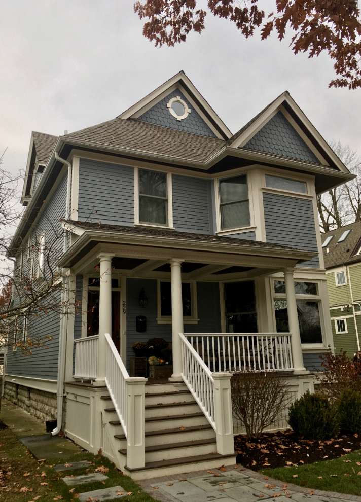 Photo of a mid-sized traditional two-storey blue house exterior in Chicago with concrete fiberboard siding, a clipped gable roof and a shingle roof.