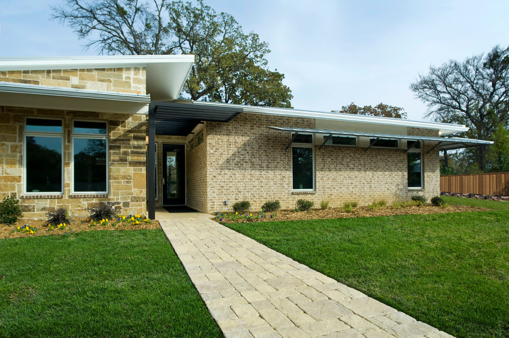 Photo of a large modern one-storey beige exterior in Dallas with stone veneer and a flat roof.