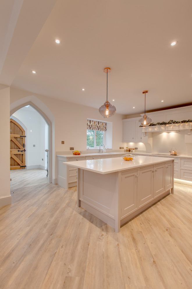 Inspiration for a large transitional u-shaped open plan kitchen in Other with a double-bowl sink, beaded inset cabinets, white cabinets, quartzite benchtops, white splashback, stainless steel appliances, light hardwood floors and with island.