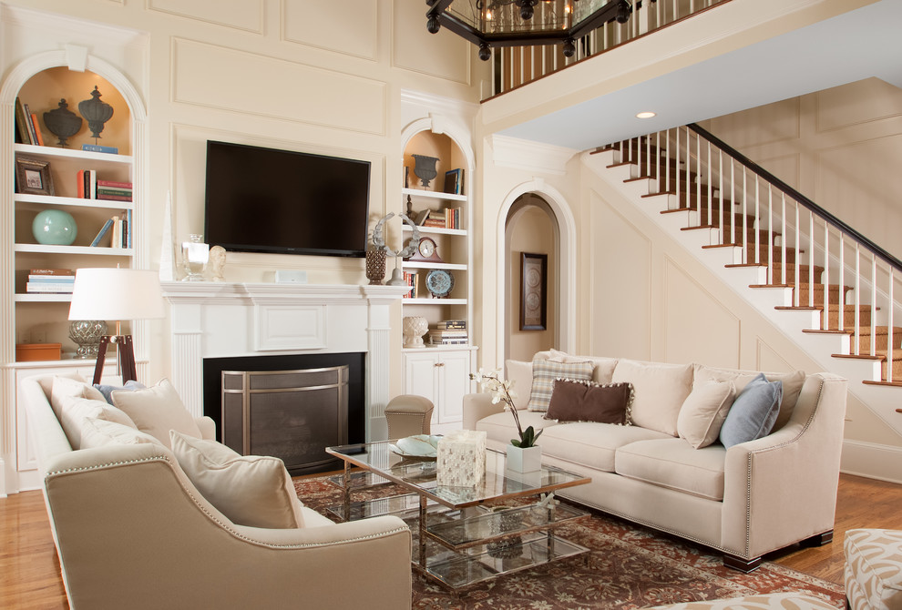 Inspiration for a large traditional living room in Atlanta with beige walls, a standard fireplace, a plaster fireplace surround, a wall-mounted tv, medium hardwood floors and brown floor.