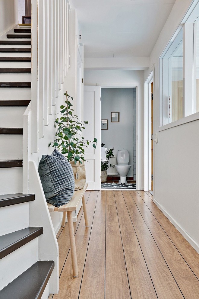 This is an example of a country hallway in Gothenburg with white walls, light hardwood floors and beige floor.