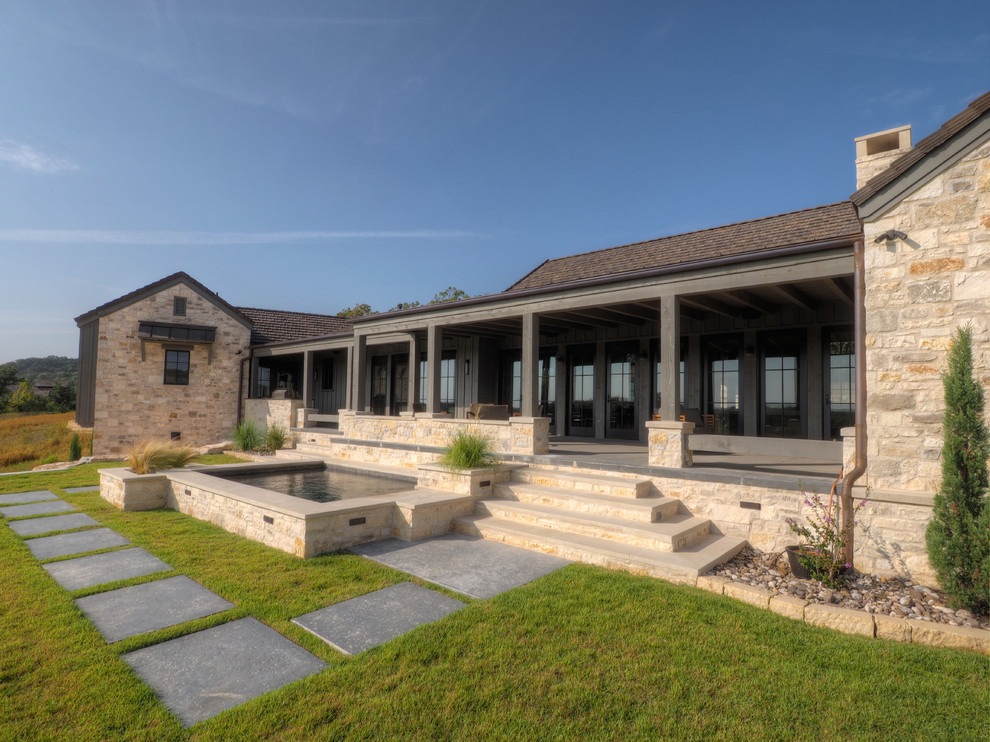 Large rustic beige two-story stone gable roof idea in Austin with a shingle roof