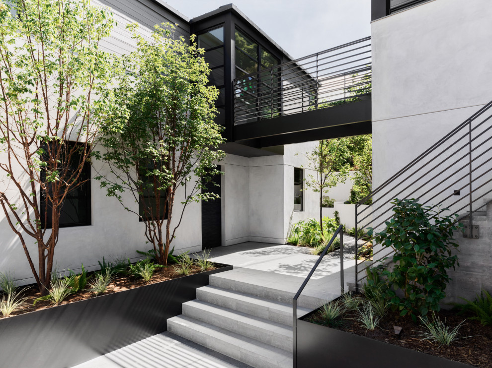 Réalisation d'une grande façade de maison blanche design en béton à un étage avec un toit gris.