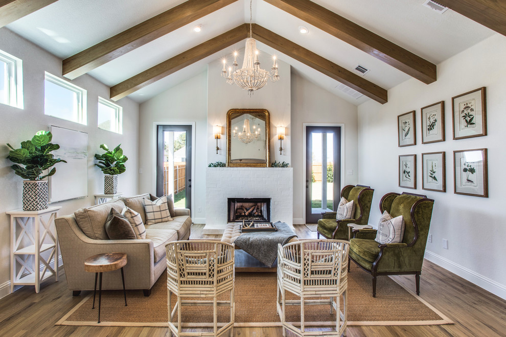 This is an example of a traditional living room in Dallas with white walls, light hardwood floors, a standard fireplace and a brick fireplace surround.
