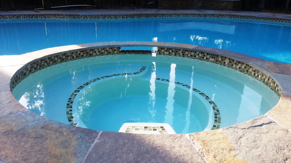 This is an example of a large contemporary backyard custom-shaped natural pool in San Francisco with a hot tub and stamped concrete.