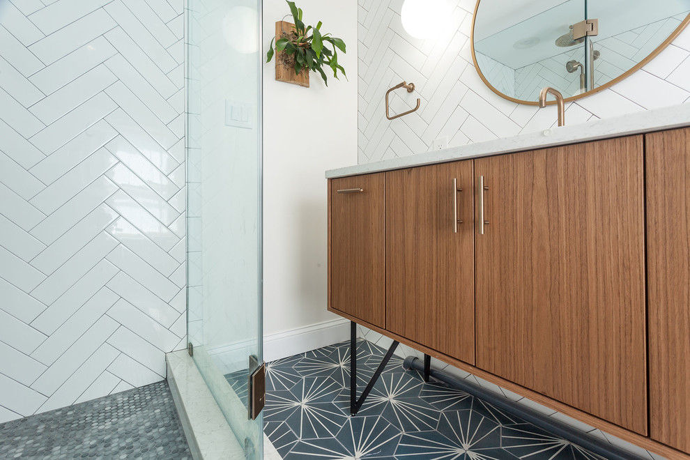Mid-sized midcentury 3/4 bathroom in DC Metro with flat-panel cabinets, medium wood cabinets, a corner shower, a two-piece toilet, white tile, subway tile, white walls, cement tiles, an undermount sink, engineered quartz benchtops, blue floor, a hinged shower door, white benchtops and brick walls.