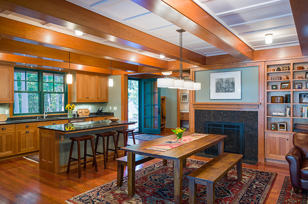 Photo of an arts and crafts dining room in Philadelphia with green walls, light hardwood floors, a standard fireplace and brown floor.