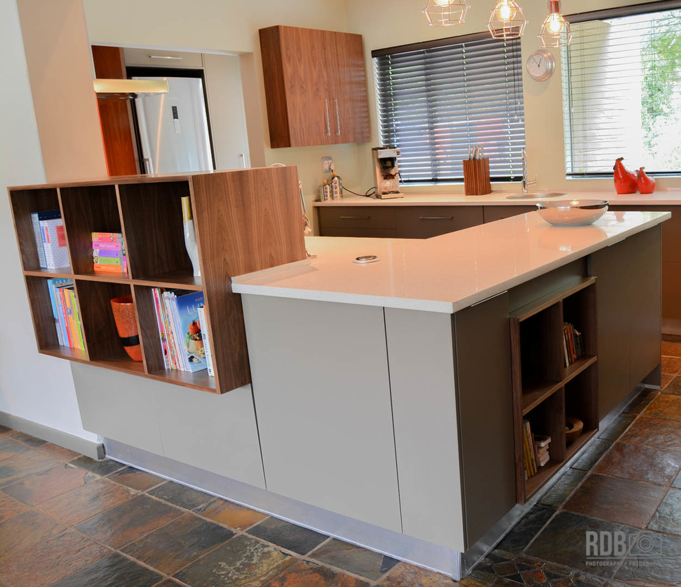 Mid-sized mountain style u-shaped slate floor enclosed kitchen photo with a drop-in sink, flat-panel cabinets, green cabinets, quartz countertops, red backsplash, glass sheet backsplash, stainless steel appliances and an island