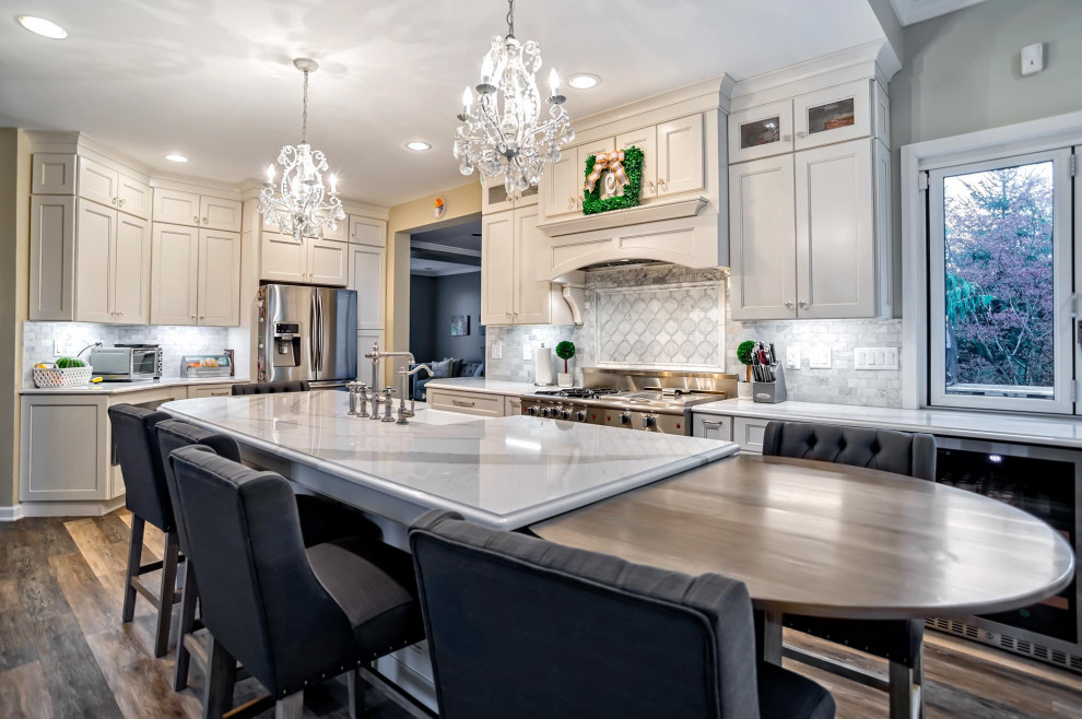 Eat-in kitchen - large transitional single-wall medium tone wood floor and brown floor eat-in kitchen idea in Philadelphia with a farmhouse sink, shaker cabinets, white cabinets, quartz countertops, gray backsplash, porcelain backsplash, stainless steel appliances, an island and white countertops