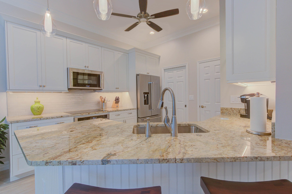 Example of a mid-sized transitional galley porcelain tile and beige floor enclosed kitchen design in Miami with a double-bowl sink, flat-panel cabinets, white cabinets, granite countertops, white backsplash, ceramic backsplash and stainless steel appliances