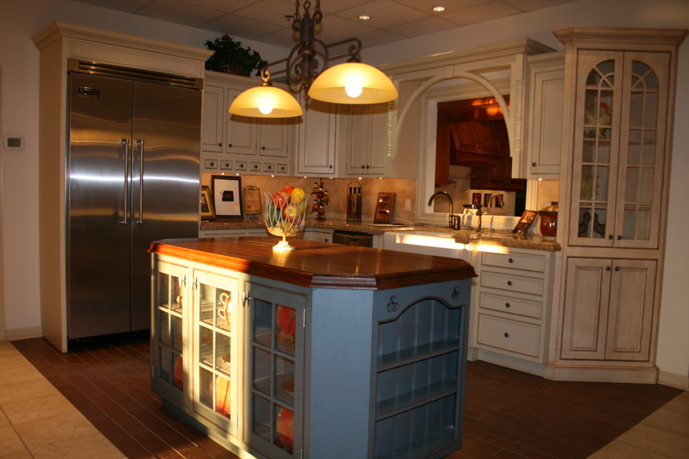 Photo of a large traditional l-shaped separate kitchen in New York with an undermount sink, raised-panel cabinets, white cabinets, granite benchtops, beige splashback, stainless steel appliances, ceramic floors and with island.