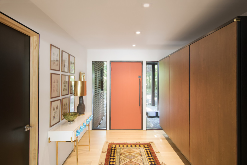 60 tals inredning av en mellanstor foajé, med vita väggar, ljust trägolv, en enkeldörr och en orange dörr