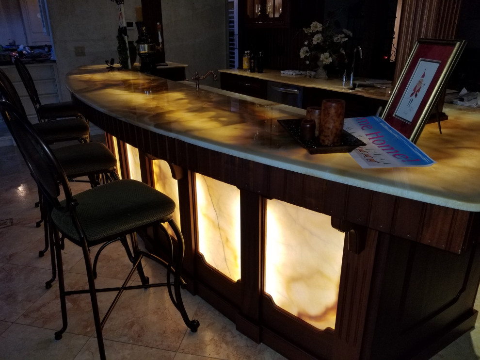 Foto di un grande angolo bar con lavandino classico con ante con bugna sagomata, ante in legno scuro, top in onice e top giallo