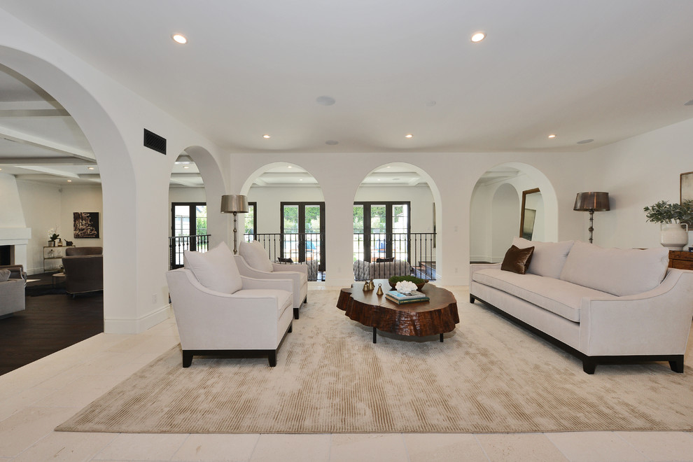This is an example of a large mediterranean open concept living room in Los Angeles with white walls, dark hardwood floors, a two-sided fireplace, a plaster fireplace surround and brown floor.