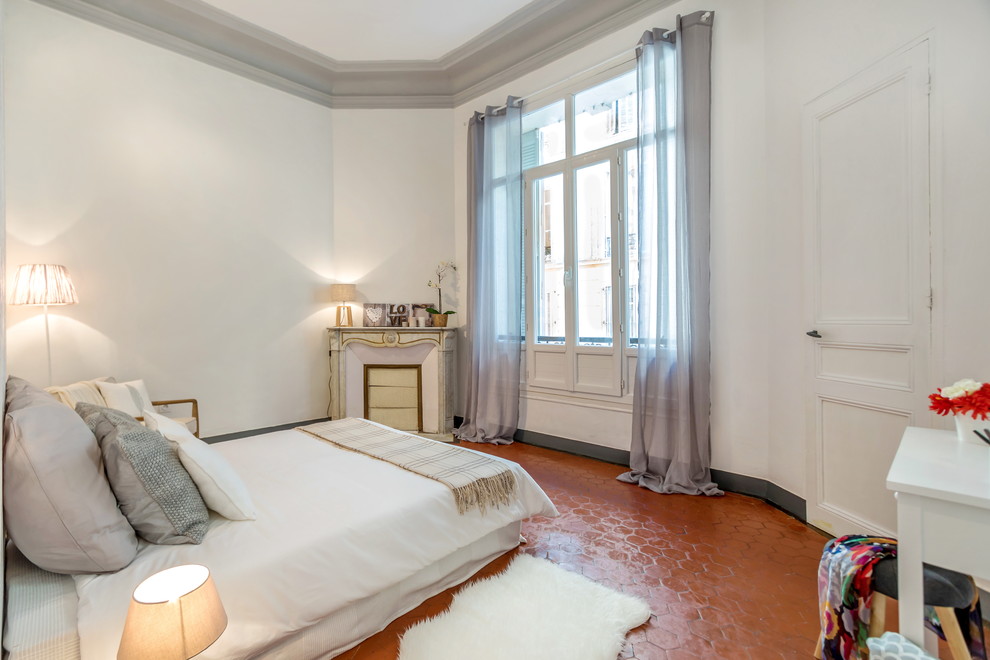 This is an example of a large transitional master bedroom in Marseille with white walls, ceramic floors, a standard fireplace and a stone fireplace surround.