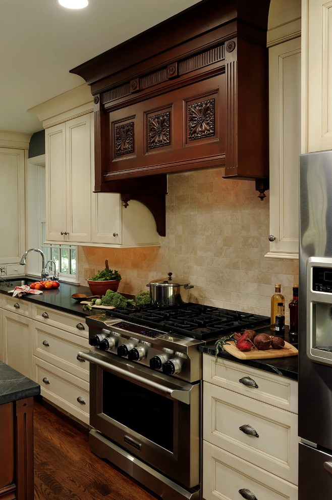 Design ideas for a mid-sized traditional u-shaped eat-in kitchen in DC Metro with an undermount sink, beaded inset cabinets, white cabinets, soapstone benchtops, beige splashback, stone tile splashback, stainless steel appliances, dark hardwood floors, multiple islands and brown floor.