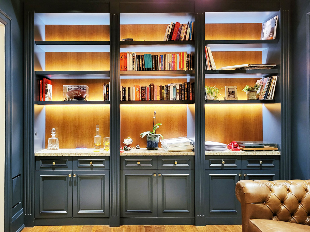 Diseño de biblioteca en casa tradicional de tamaño medio con paredes azules, suelo de madera en tonos medios, suelo marrón y panelado
