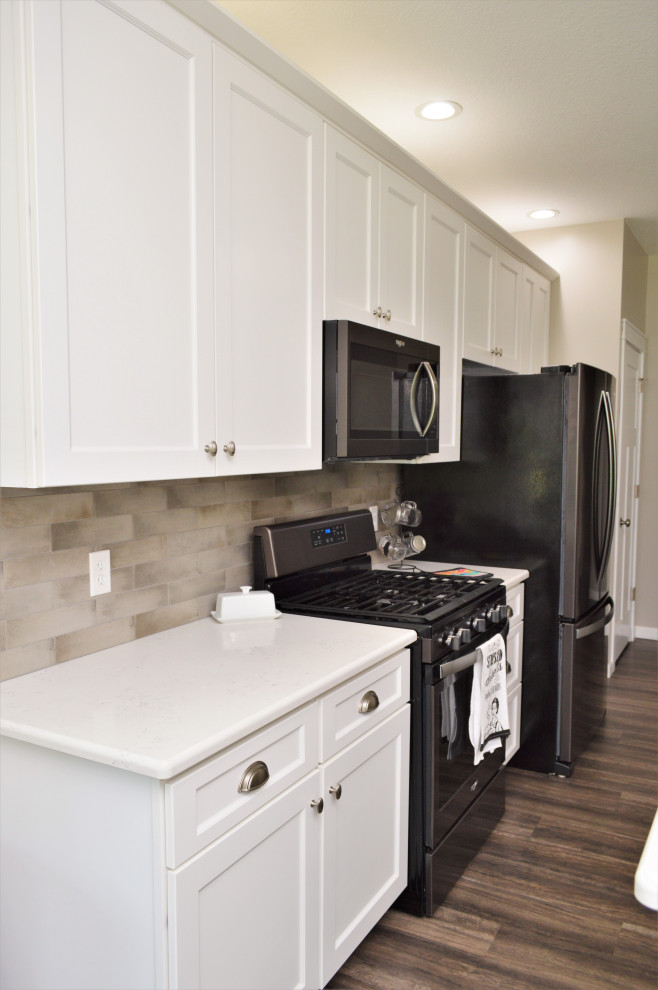 Open concept kitchen - mid-sized transitional single-wall open concept kitchen idea with a drop-in sink, shaker cabinets, white cabinets, quartzite countertops, beige backsplash, stainless steel appliances, an island and white countertops