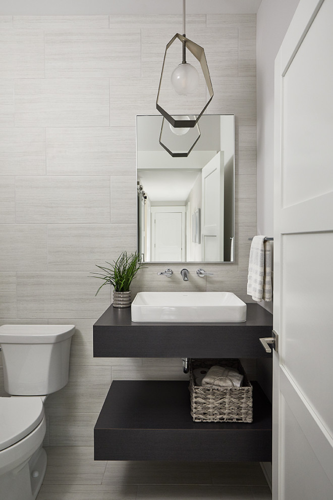 Design ideas for a transitional powder room in Grand Rapids with open cabinets, dark wood cabinets, gray tile, porcelain tile, grey walls, porcelain floors, an integrated sink, wood benchtops, grey floor, brown benchtops and a floating vanity.
