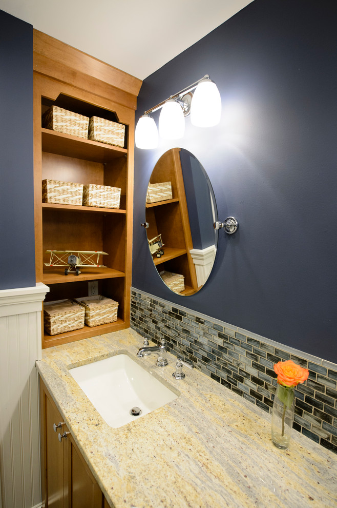 Inspiration for a mid-sized transitional kids bathroom in Boston with recessed-panel cabinets, medium wood cabinets, a drop-in tub, a one-piece toilet, blue tile, glass sheet wall, blue walls, ceramic floors, an undermount sink and granite benchtops.