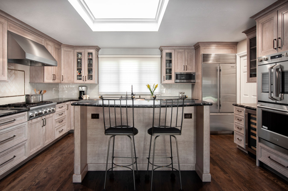 Design ideas for a large traditional u-shaped eat-in kitchen in San Francisco with recessed-panel cabinets, light wood cabinets, quartzite benchtops, white splashback, ceramic splashback, stainless steel appliances, dark hardwood floors, with island, brown floor and black benchtop.