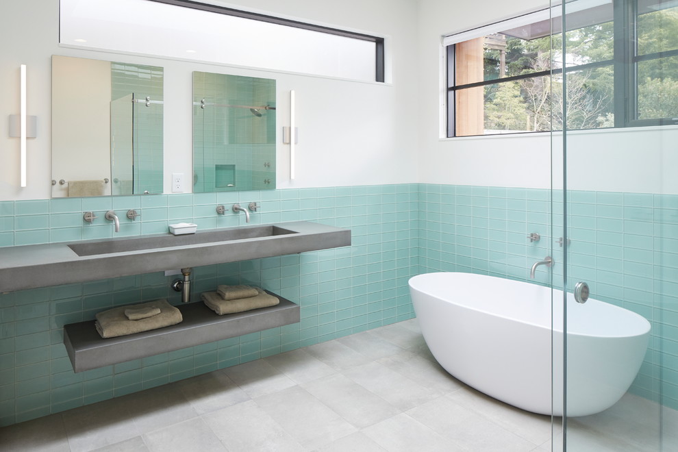 This is an example of a contemporary master bathroom in Portland with open cabinets, grey cabinets, a freestanding tub, a corner shower, blue tile, subway tile, white walls, porcelain floors, an integrated sink, concrete benchtops, grey floor, a hinged shower door and grey benchtops.