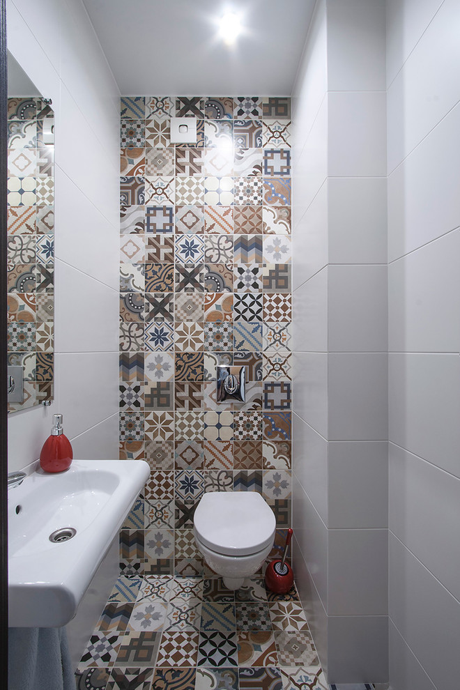This is an example of a small contemporary powder room in Saint Petersburg with a wall-mount toilet, ceramic tile, multi-coloured walls, mosaic tile floors, a console sink and multi-coloured floor.