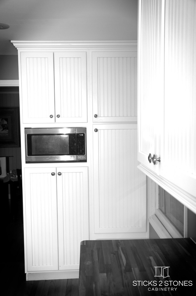 Open concept kitchen - small traditional galley light wood floor open concept kitchen idea with a double-bowl sink, shaker cabinets, white cabinets, wood countertops, white backsplash, subway tile backsplash, stainless steel appliances, green walls and a peninsula
