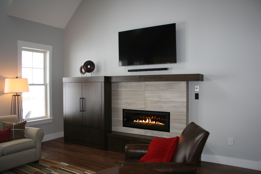 Photo of a mid-sized modern open concept living room in Other with grey walls, dark hardwood floors, a ribbon fireplace, a tile fireplace surround, a wall-mounted tv, brown floor and vaulted.