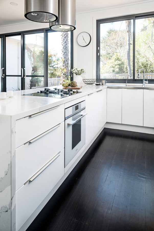 Inspiration for a mid-sized modern u-shaped eat-in kitchen in Melbourne with an integrated sink, flat-panel cabinets, white cabinets, quartz benchtops, black appliances, dark hardwood floors, a peninsula, black floor and yellow benchtop.