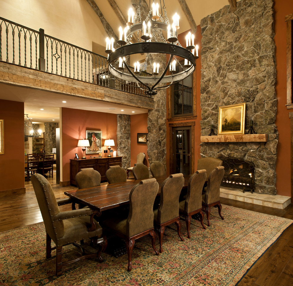 Country dining room in Other with a stone fireplace surround and brown walls.