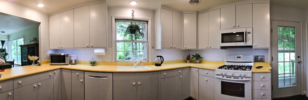 Mid-sized midcentury u-shaped separate kitchen in New York with an undermount sink, flat-panel cabinets, white cabinets, laminate benchtops, white splashback, white appliances, linoleum floors and purple floor.