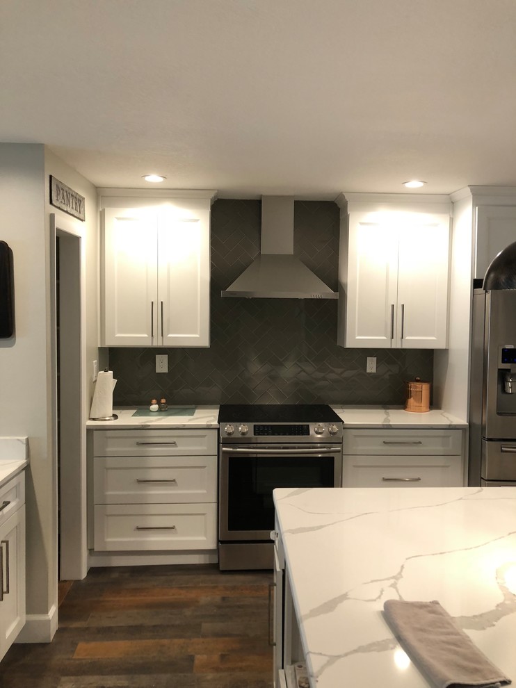 Large country l-shaped eat-in kitchen in Tampa with a farmhouse sink, recessed-panel cabinets, white cabinets, quartzite benchtops, grey splashback, ceramic splashback, stainless steel appliances, dark hardwood floors, with island, brown floor and white benchtop.