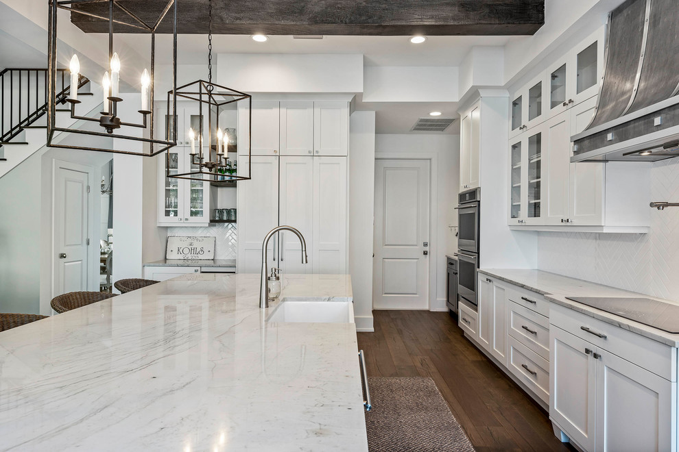 Example of a large transitional l-shaped medium tone wood floor eat-in kitchen design in Orlando with a farmhouse sink, shaker cabinets, white cabinets, marble countertops, white backsplash, mosaic tile backsplash, stainless steel appliances, an island and white countertops