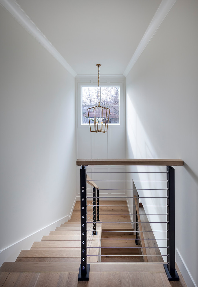 Imagen de escalera en U de estilo de casa de campo de tamaño medio con escalones de madera, contrahuellas de madera, barandilla de cable y panelado