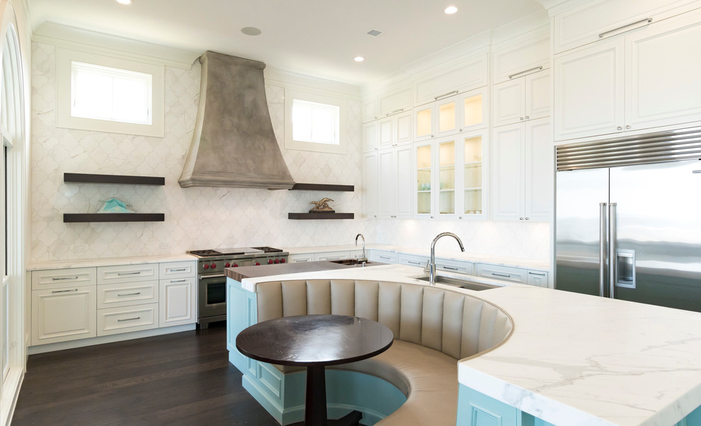 This is an example of a transitional l-shaped eat-in kitchen in Miami with an undermount sink, glass-front cabinets, white cabinets, white splashback, stainless steel appliances and dark hardwood floors.
